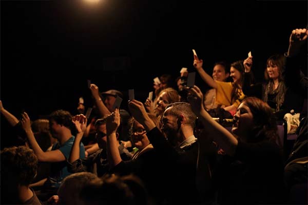 Photograph of a crowd holding up pieces of paper.
