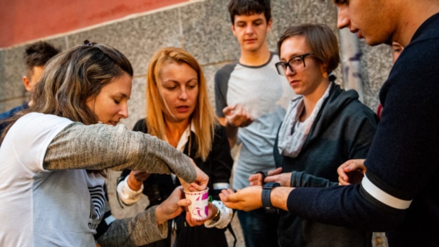 Photograph of a group of people picking something from a cup.