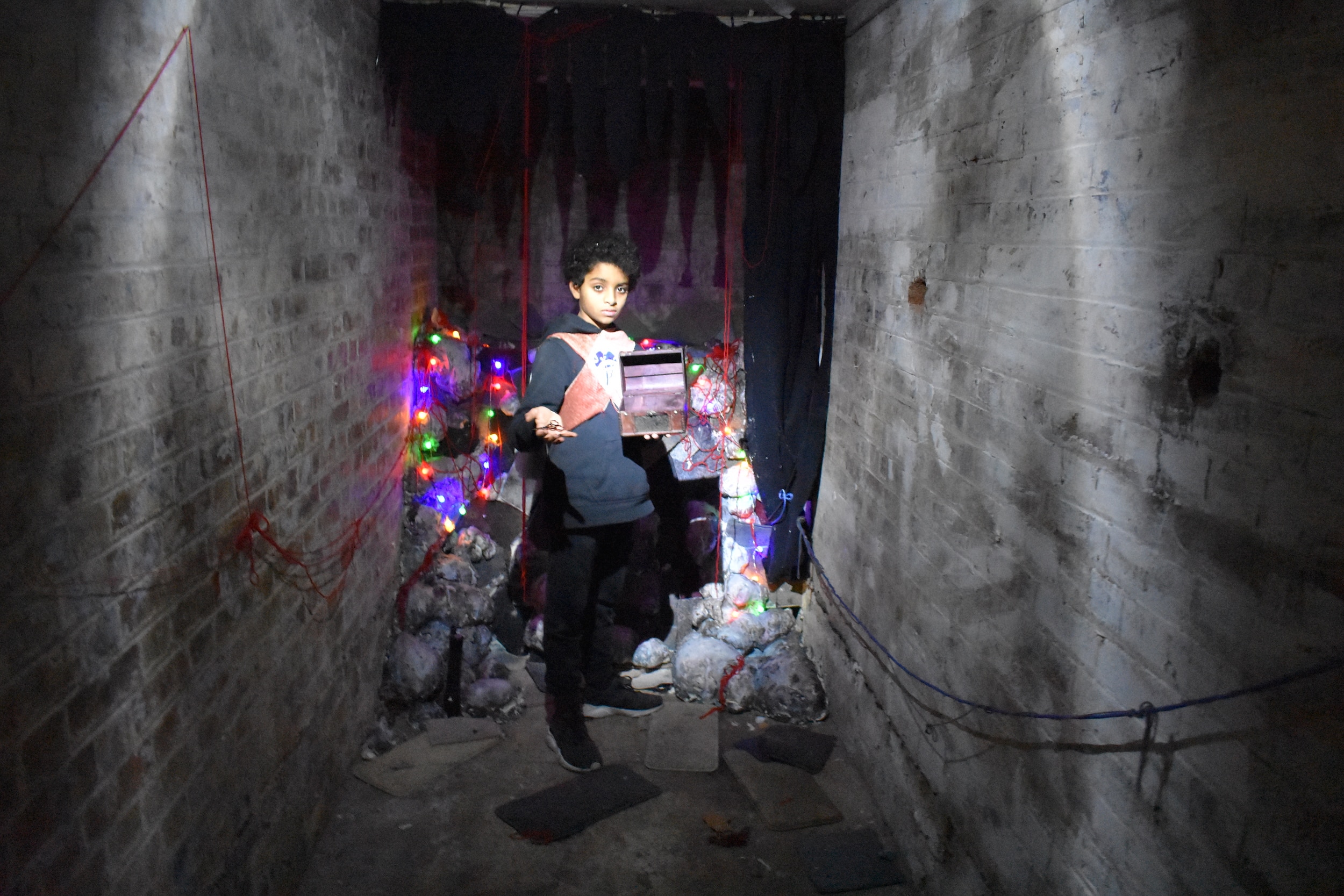 Photograph of a young boy holding a treasure chest in a decorated basement.