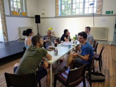 Photograph of a group of people sat around a white table drinking tea.