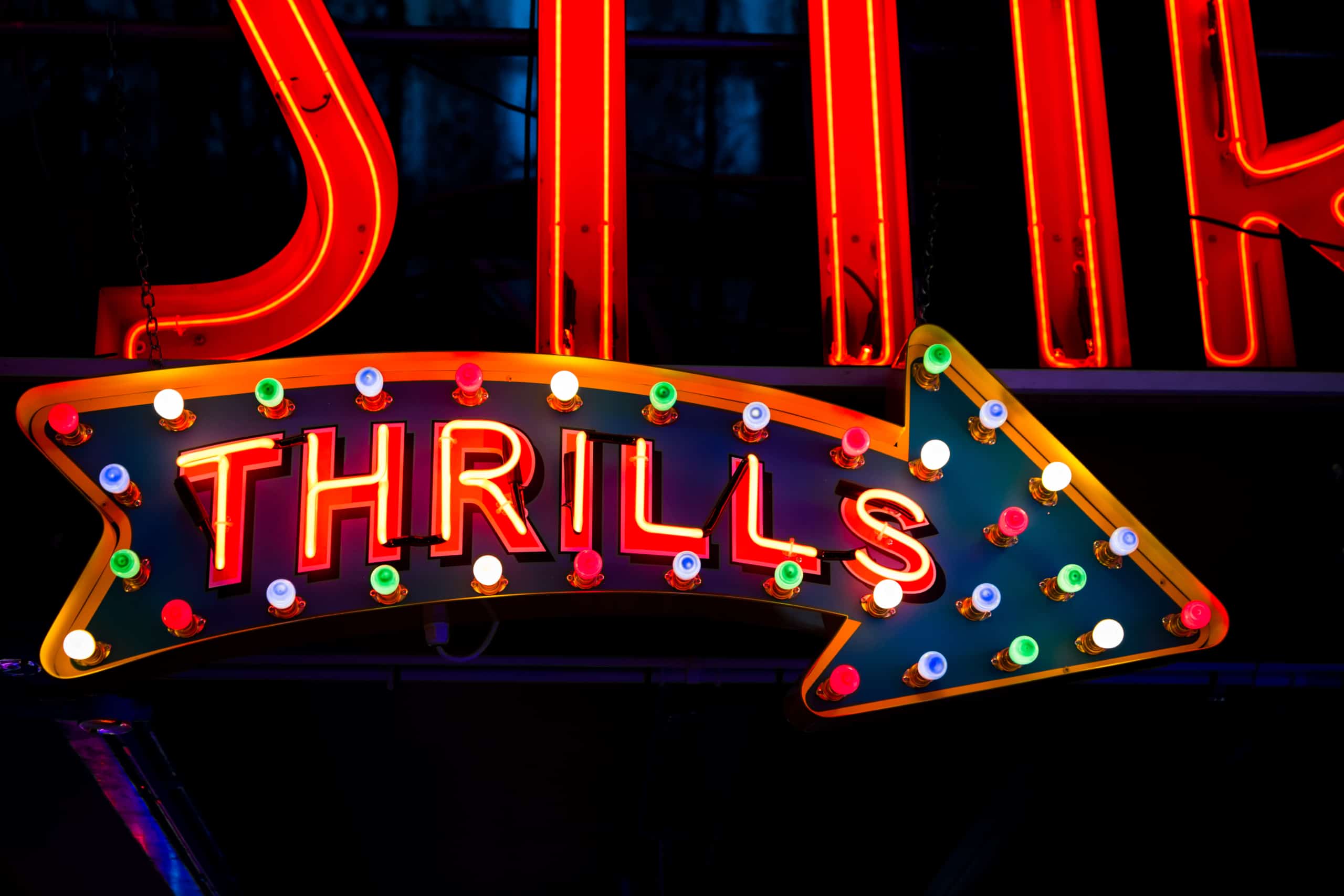 Photograph of a neon sign that reads 'Thrills'.