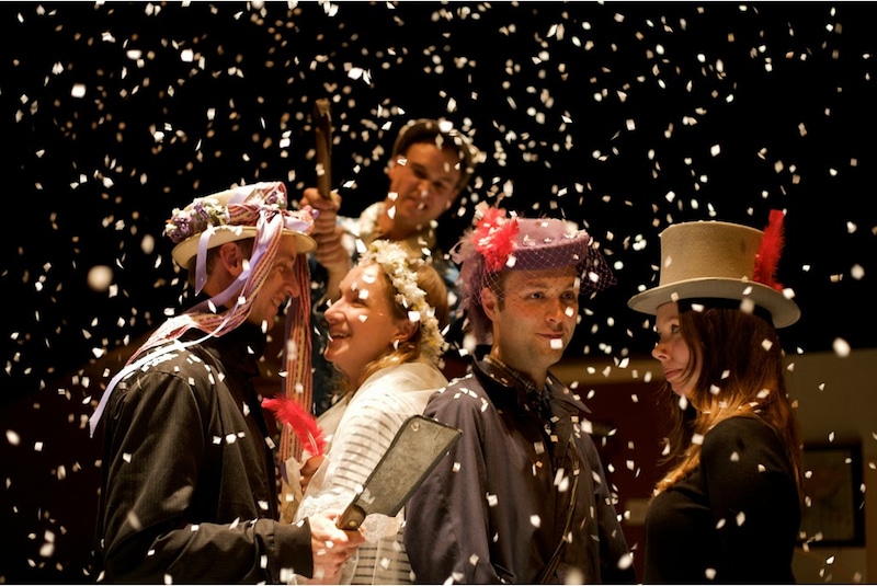 Photograph of people in costumes with confetti falling on them.